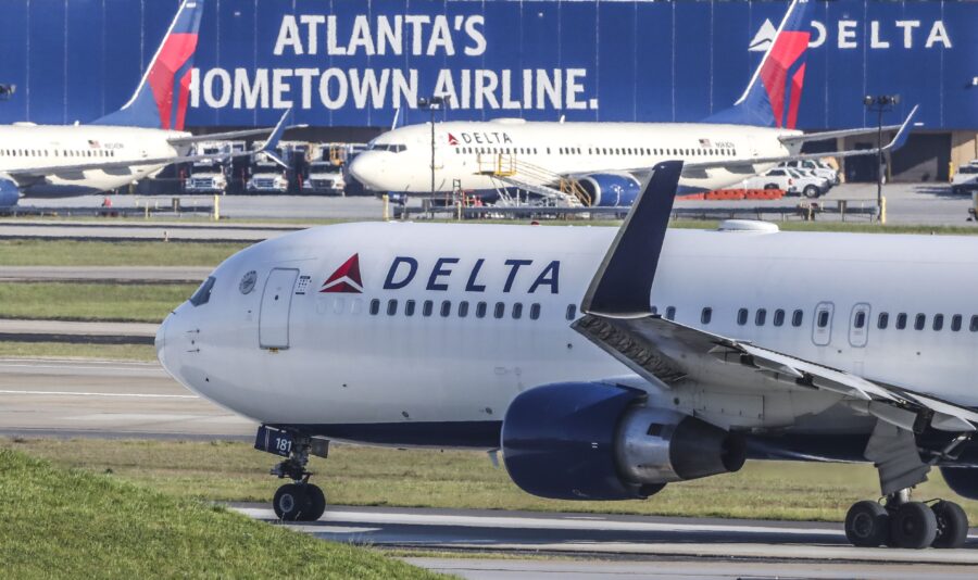 Delta airplane at Atlanta airport, showcasing branding and busy runway, with aircraft and vehicles.