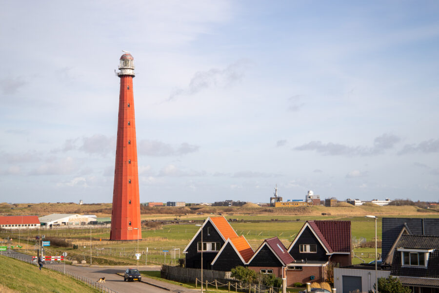 Lighthouse De Lange Jaap in Den Helder, Netherlands, stands tall against a clear blue sky, guiding ships safely to shore.