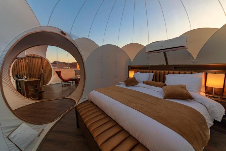 Luxury desert bubble hotel room interior with dome tent, king bed, glamping suite amenities.