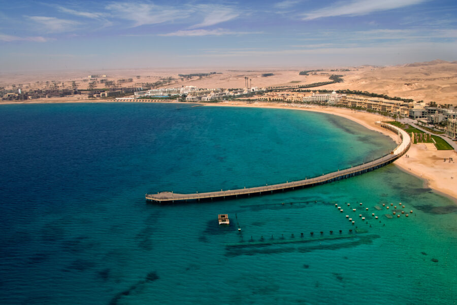 Aerial view of Sahl Hasheesh Red Sea resort bay, sandy beach, turquoise water, desert backdrop.