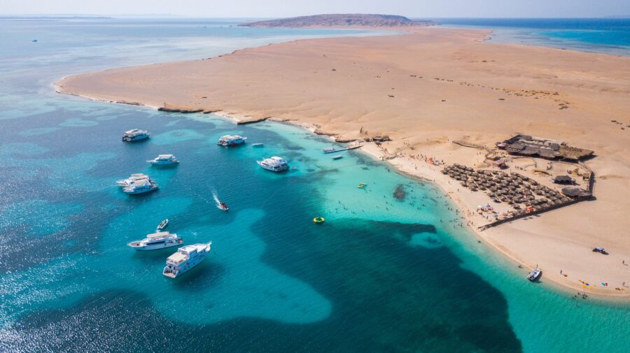 Aerial view of Giftun Island beach resort with yachts, turquoise Red Sea waters and desert landscape.