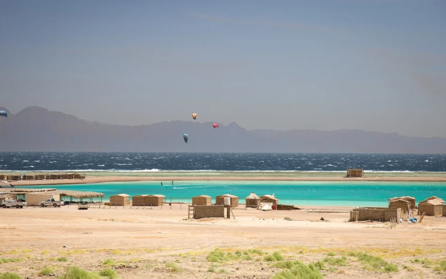 Desert kitesurfing lagoon in Dahab with rustic beach camp, turquoise water and Sinai mountains.