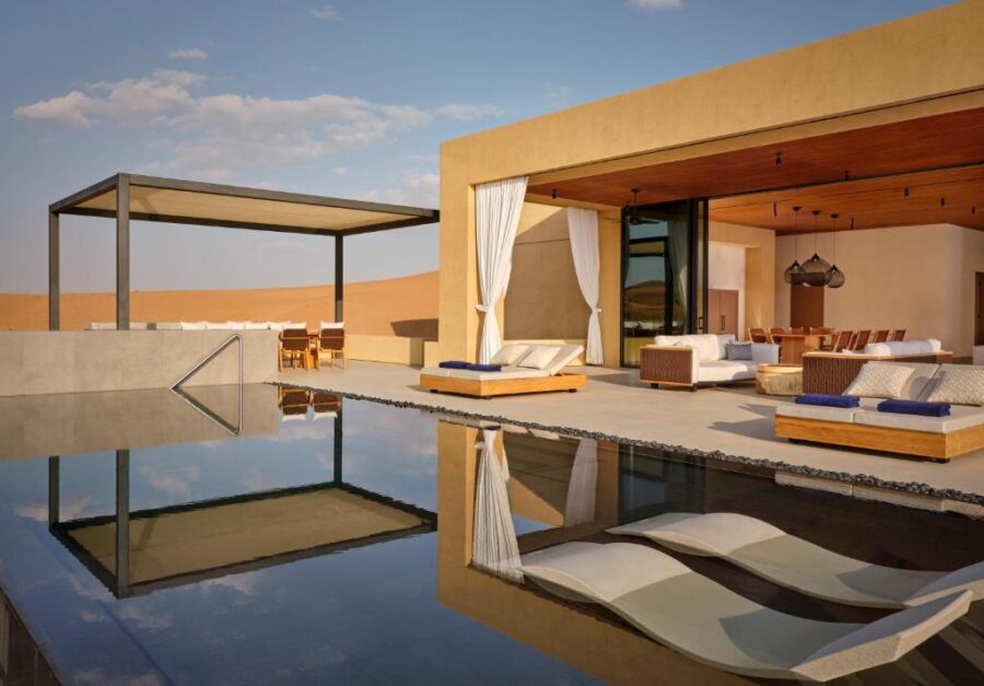Luxury desert villa with infinity pool, modern outdoor lounge, and panoramic sand dune views.