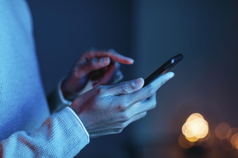 Person using smartphone with focus on hands and cozy lighting.
