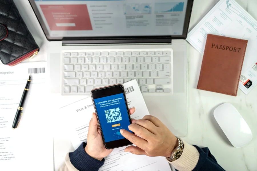 Digital vaccine certificate and travel documents on organized workspace for international travel.