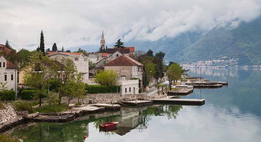 Small boat secured to a dock in front of the picturesque town of Dobrota, Kotor, Montenegro.