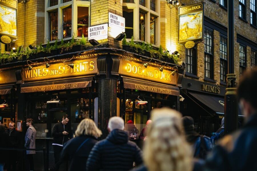 Lively London pub Dog and Duck in Soho with people enjoying the vibrant street scene.