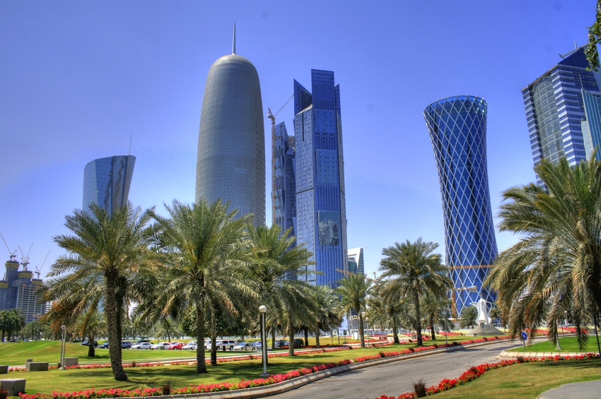 Modern Doha skyline with skyscrapers, lush gardens, and ongoing construction.
