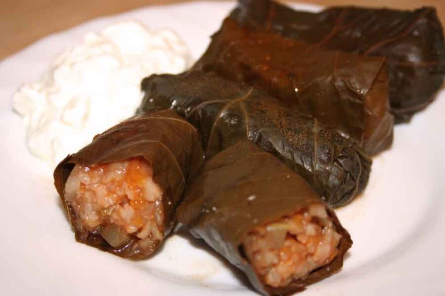 Stuffed grape leaves with rice and meat filling, served with creamy yogurt sauce.