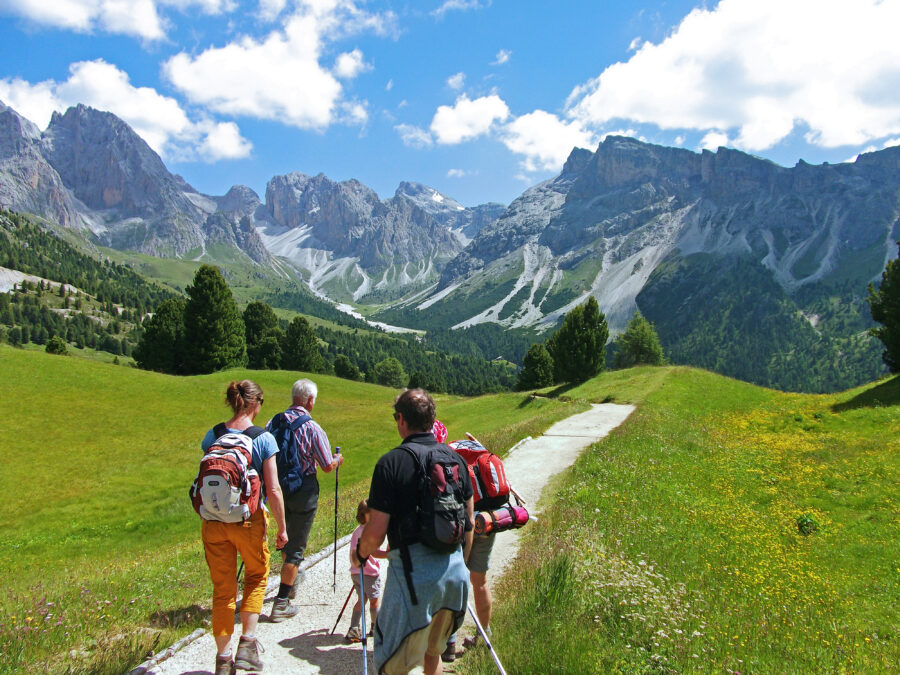 Tourists enjoying a family hike in the breathtaking Dolomites, with towering peaks and lush scenery in the background