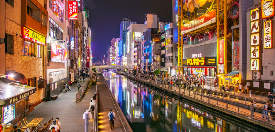 Night view of Dotonbori district in Osaka, Japan, filled with colorful neon signs and lively crowds enjoying the atmosphere.
