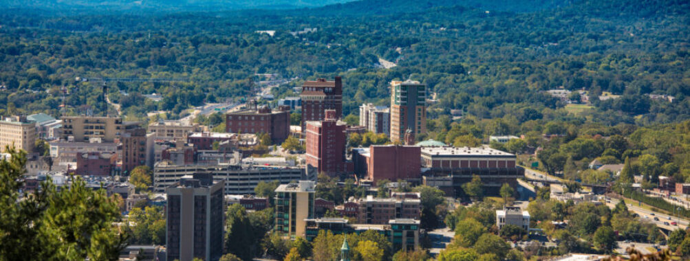 Vibrant downtown Asheville, North Carolina, framed by the majestic Blue Ridge Mountains on a sunny day.