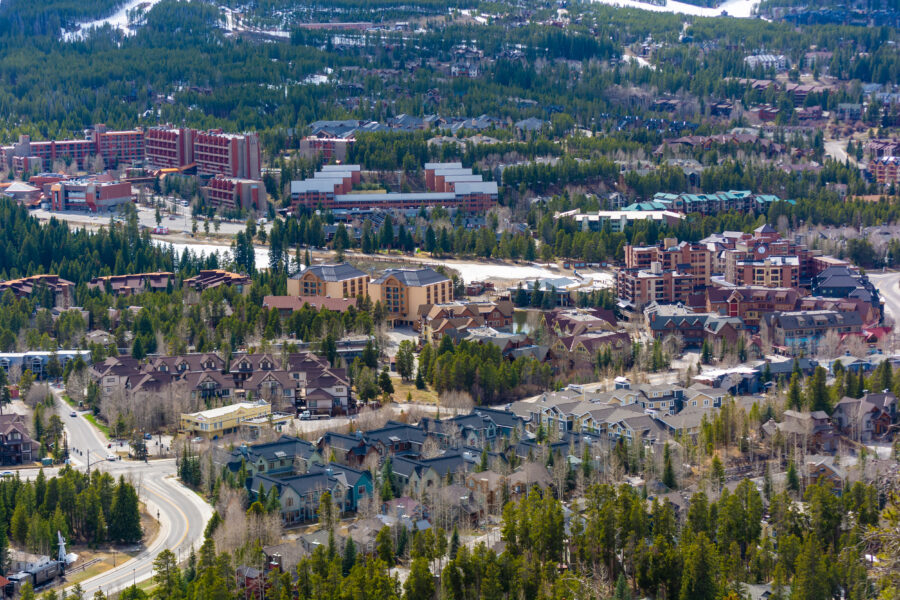 Daytime winter view of downtown Breckenridge, Colorado, with snow-dusted streets and towering mountains behind.