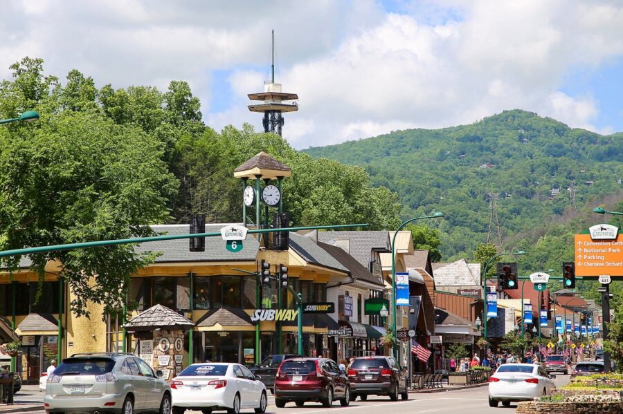 Downtown Gatlinburg, Tennessee, showcasing a lively street filled with cars and a clock tower marking the time.