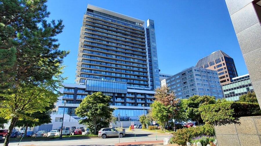 Tall building with numerous windows surrounded by trees, showcasing a view of downtown Halifax.