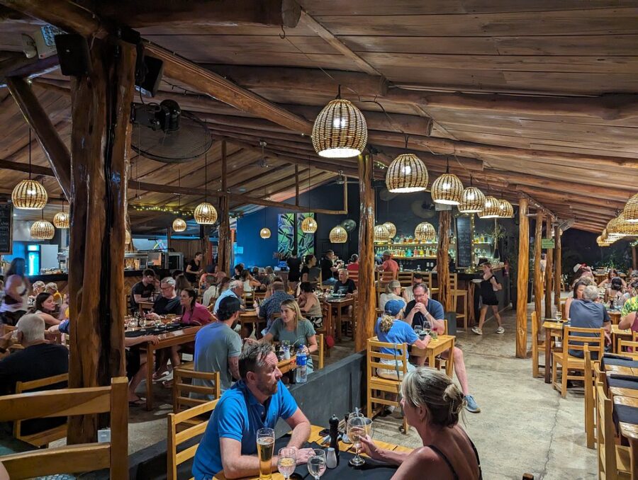 Interior view of Dragonfly Bar & Grill in Tamarindo, showcasing a vibrant atmosphere with wooden decor and seating