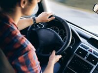Driver grips steering wheel in modern car interior