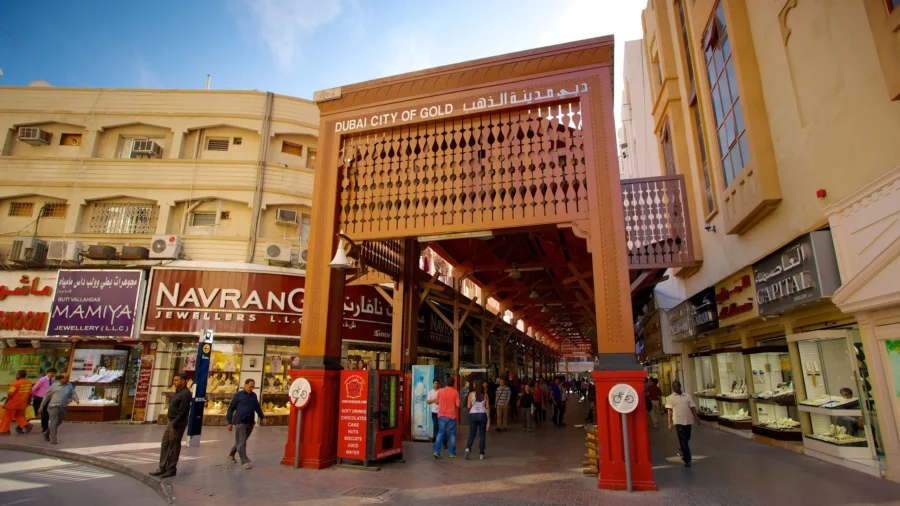 Bustling Dubai Gold Souk: Ornate entrance, vibrant shops, diverse shoppers.