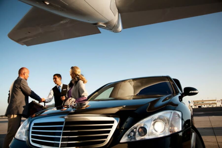 People gather by a car and an airplane, highlighting Dubai's private vehicle hire service with skilled drivers.