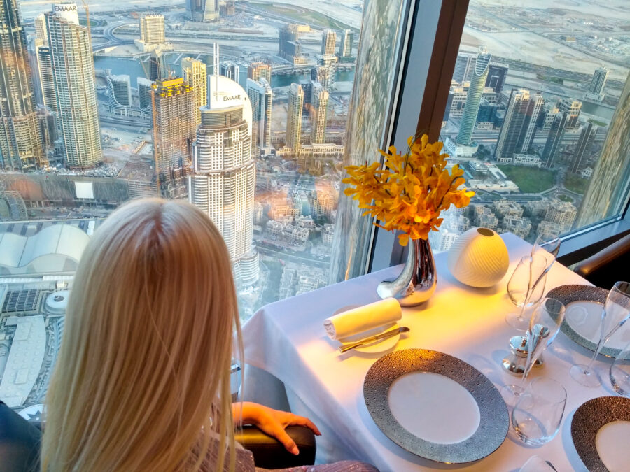 The blonde, waiting for breakfast at a table in a restaurant, looks out the window at magnificent Dubai