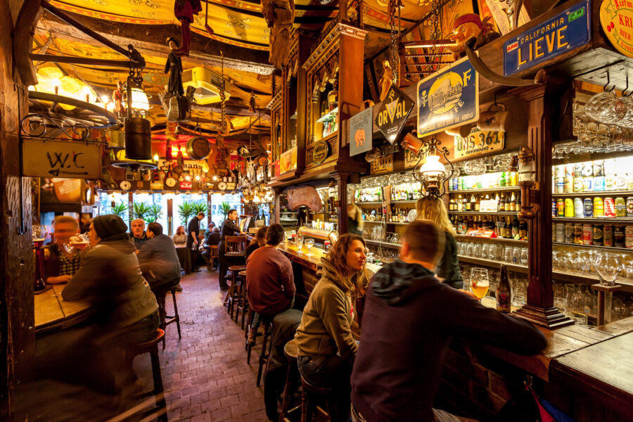 Dulle Griet Ghent pub interior with warm lighting, wooden bar, patrons, and vintage decor.