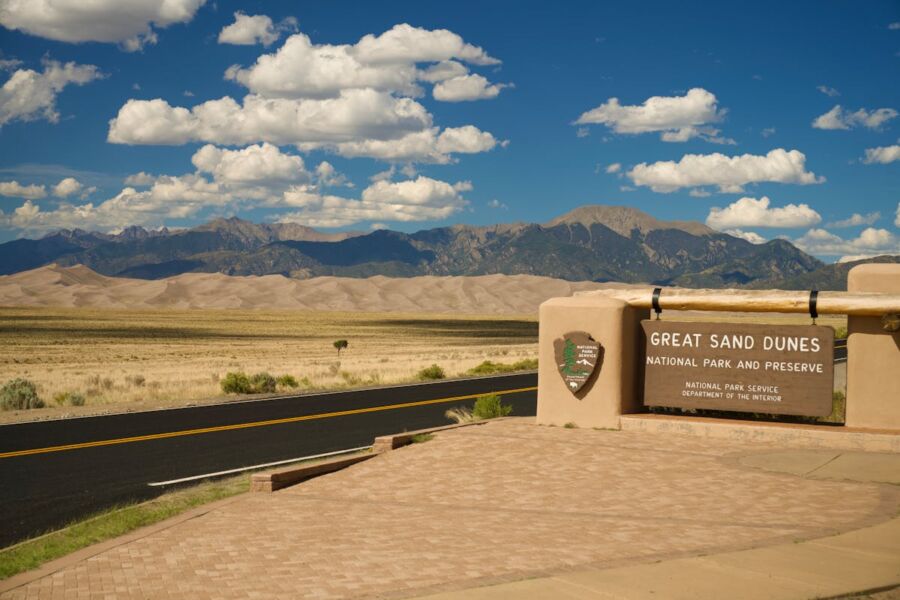 Great Sand Dunes National Park entrance, dunes, mountains, vibrant sky, Colorado landscape.