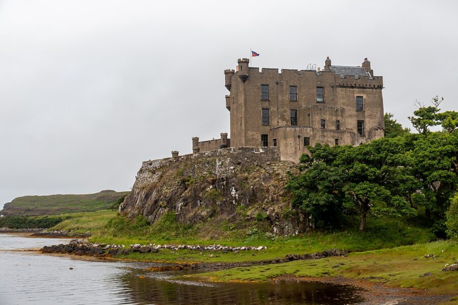 Dunvegan Castle perched on a hill, overlooking a serene body of water on the Isle of Skye.
