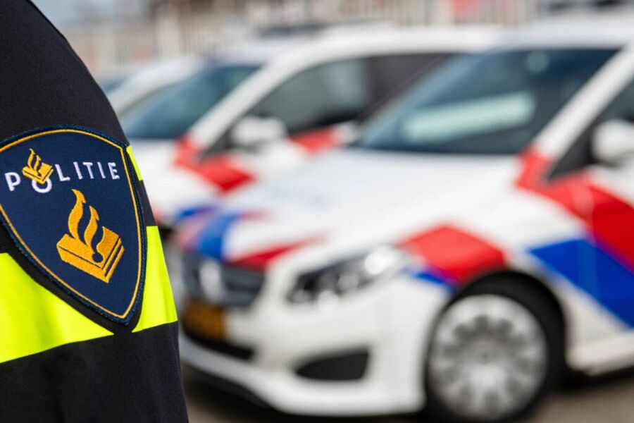 Close-up of Dutch police uniform shoulder patch with cars in the background.