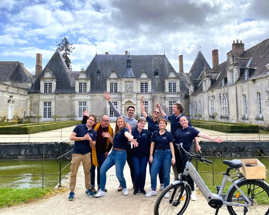 Tour participants pose together in front of a majestic castle, capturing a moment from their E-Bike tour to Chambord.
