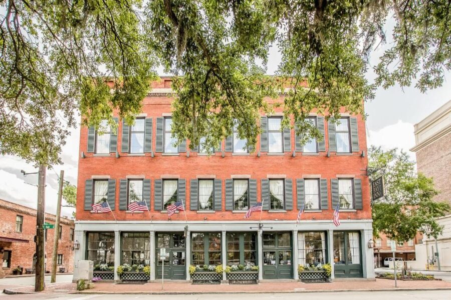 Historic East Bay Inn, a charming old brick building, stands at the corner of a street in Savannah's Historic Inns collection.
