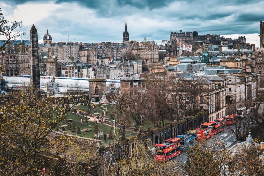 Panoramic view of Edinburgh featuring historic architecture, vibrant buses, and the iconic castle.