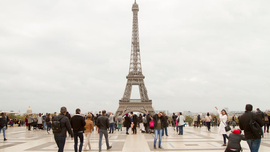 Eiffel Tower in Paris from plaza with tourists under overcast sky.