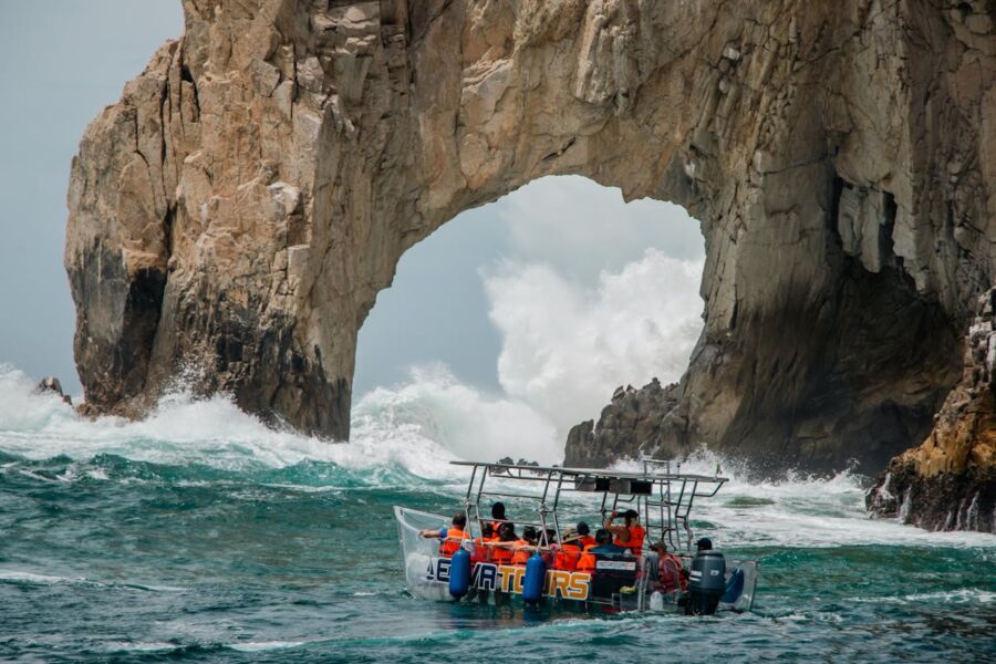 Lands End Cabo San Lucas arch, tourist boat, vibrant sea, dramatic sky.