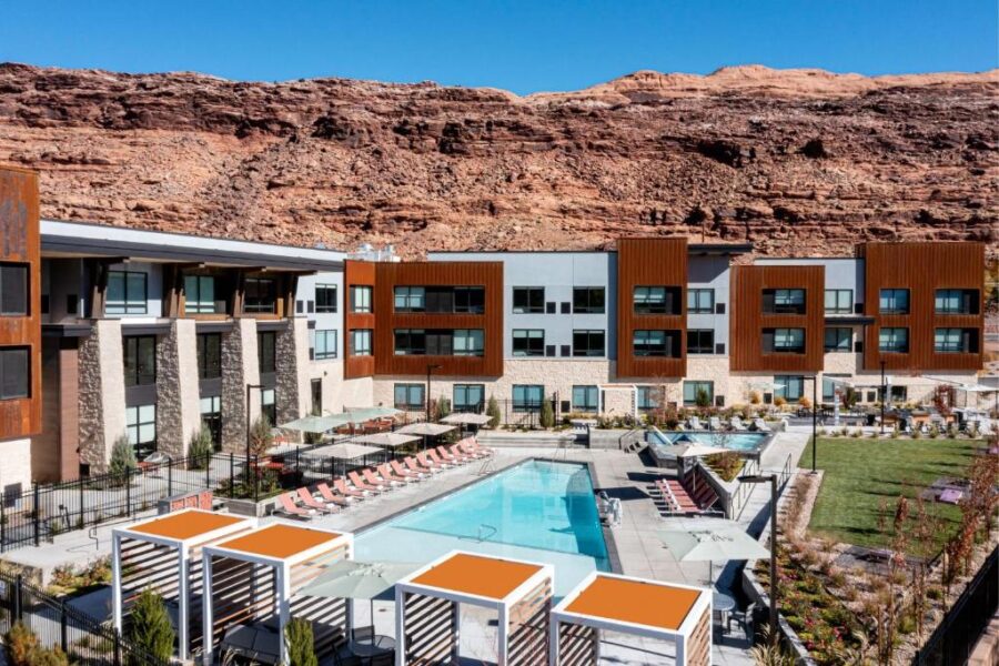 Element Moab resort nestled at the base of a canyon in Utah, surrounded by stunning red rock formations and desert landscape.
