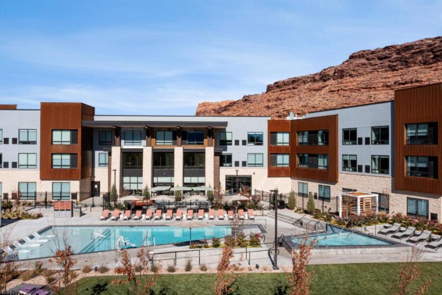 The pool area at Element Moab, a new apartment complex in Utah, featuring lounge chairs and a scenic backdrop.