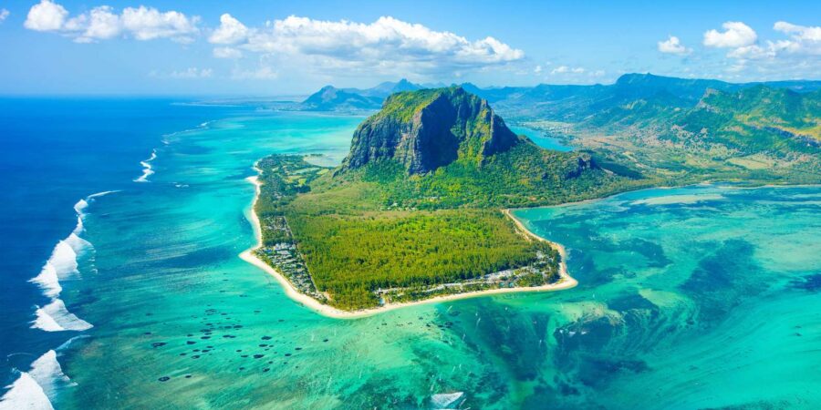 Aerial view of Le Morne Brabant mountain, tropical lagoon, coral reef, and lush Mauritius coastline.