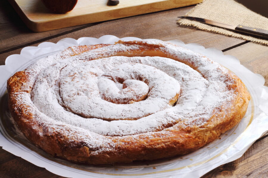 Close-up of a fluffy Ensaimada de Mallorca, showcasing its spiral shape and dusting of powdered sugar on top