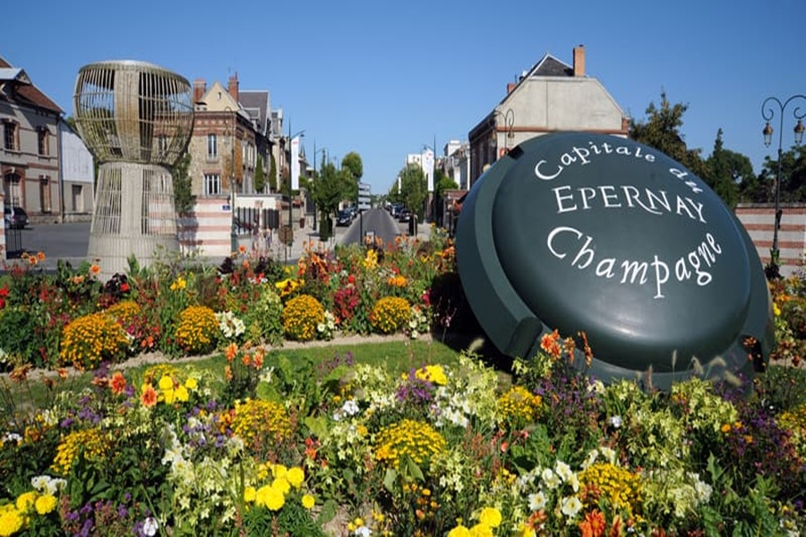 Épernay champagne roundabout with flowers and giant bottle cap sculpture.