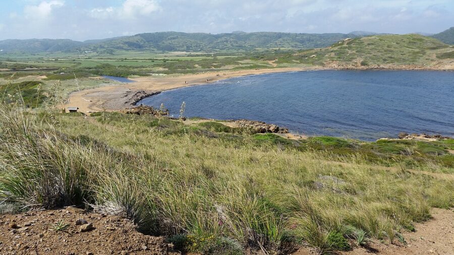 In Es Mercadal, Menorca, a rider on horseback travels down a hill, showcasing the scenic panorama of the area.