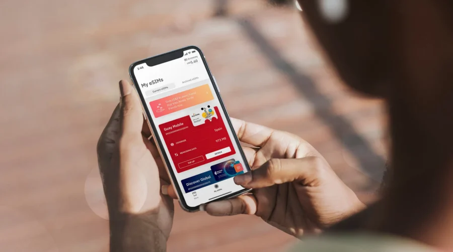 User managing eSIM plans on smartphone app outdoors with a focus on Guy Mobile plan.