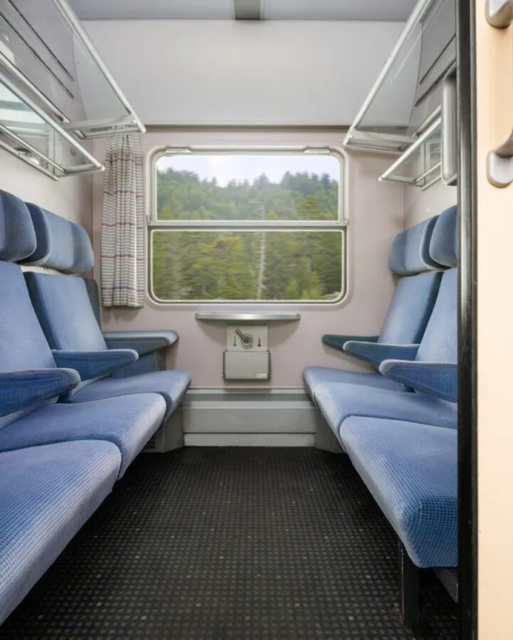 Cozy sleeper train seats in a European train, showcasing plush upholstery and individual reading lights for passengers.
