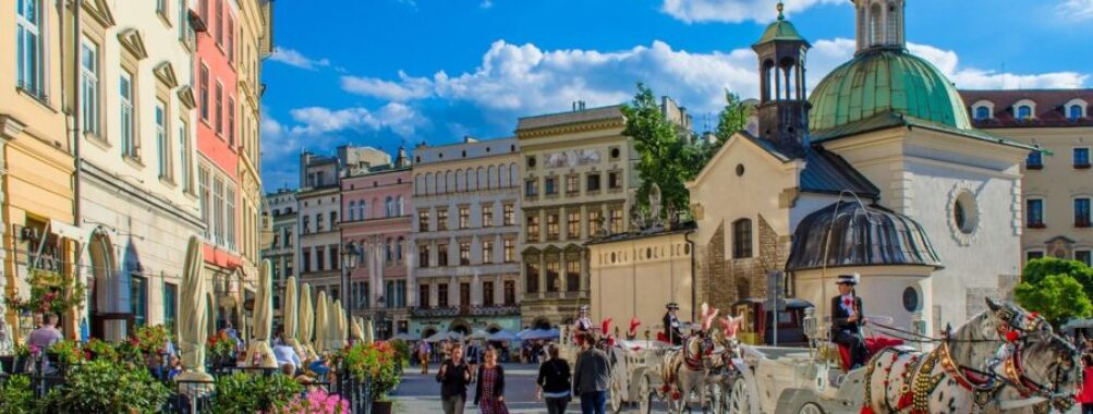 Charming historic European street with pastel buildings, cafes, church, and cobbled road.