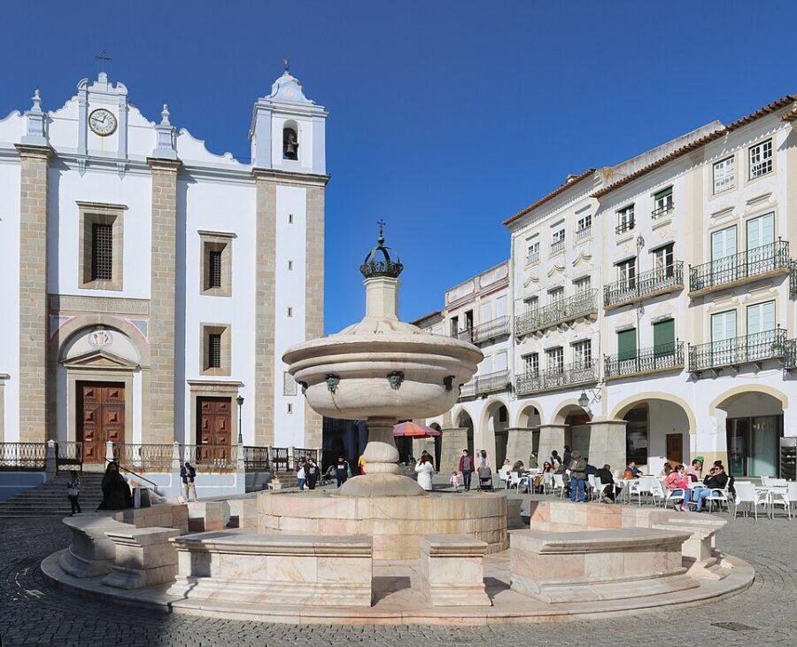 Evora's Praca do Giraldo features a prominent white building with a clock tower, highlighting its architectural significance.