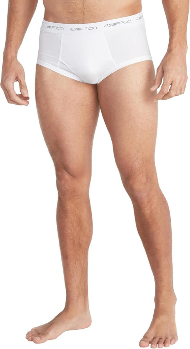 Man is modeling ExOfficio Give-N-Go white briefs with "ExOfficio" on the waistband. The image focuses on the lower torso and legs, presenting a neutral and clean look.