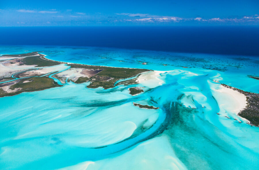 Aerial view of Exuma, Bahamas, showcasing turquoise waters and lush green islands under a clear blue sky