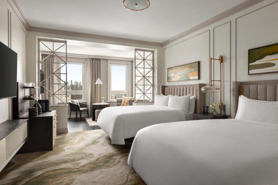 Fairmont Chateau Lake Louise room with two comfortable beds and a television, perfect for relaxation.
