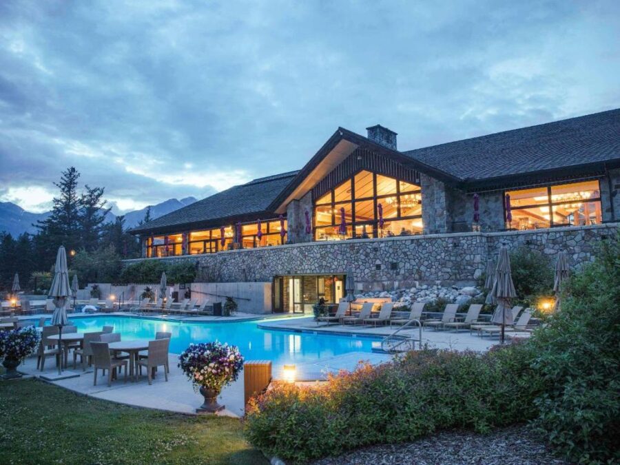 Fairmont Jasper Park Lodge nestled by a tranquil lake, surrounded by stunning mountains, in Jasper, Canada.
