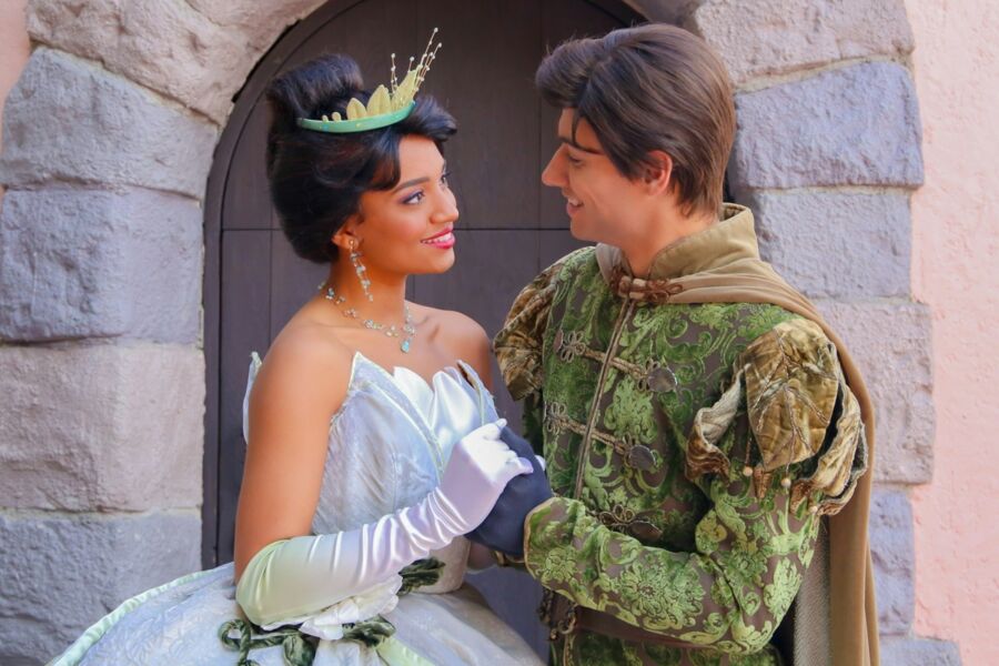Fairy tale couple in regal attire under stone archway, castle setting, magical romance.