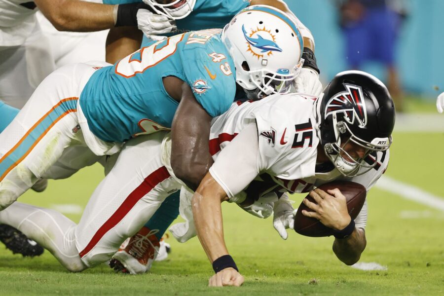 Miami Dolphins tackle Atlanta Falcons player, highlighting NFL football action.