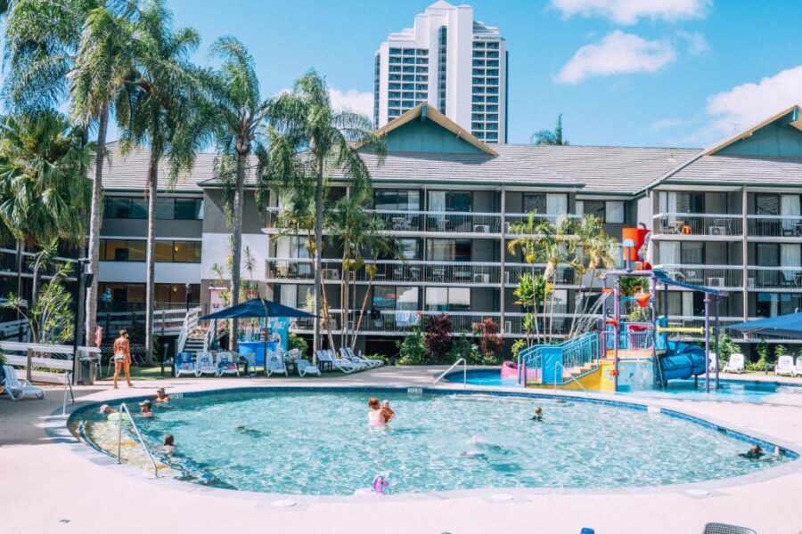 Family-friendly Gold Coast resort pool with kids water play area, lounge chairs and palm trees.